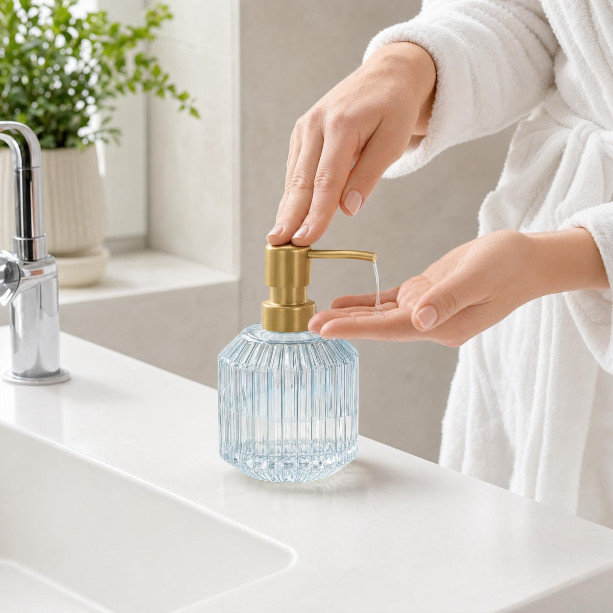 Hand drückt Seifenspender aus Riffelglas am Waschbecken im Bad.