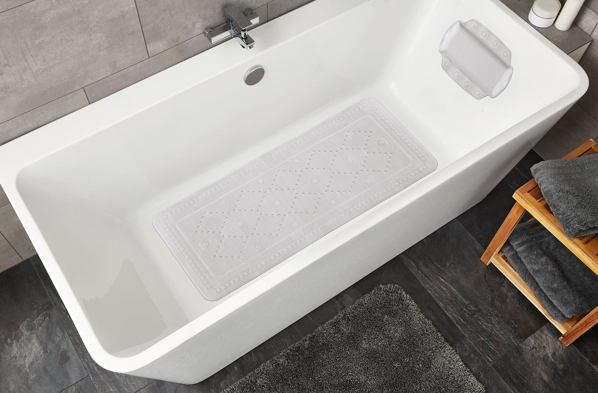 Weiße Badewanne mit rutschfester Badematte und grauen Badtextilien