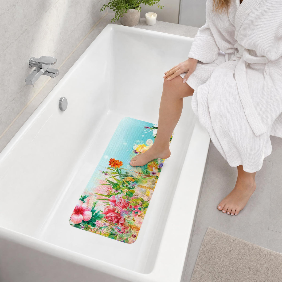 Frau im Bademantel testet bunte florale Antirutschmatte in Badewanne.