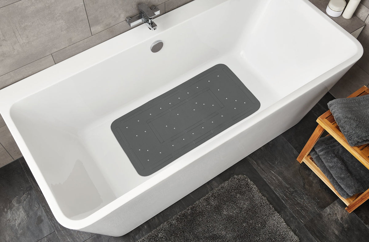 Weiße Badewanne mit grauer rutschfester Duschmatte und grauem Teppich