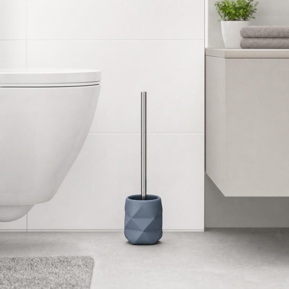 Eine blaue WC-Bürste mit Halter steht neben der Toilette im Bad.