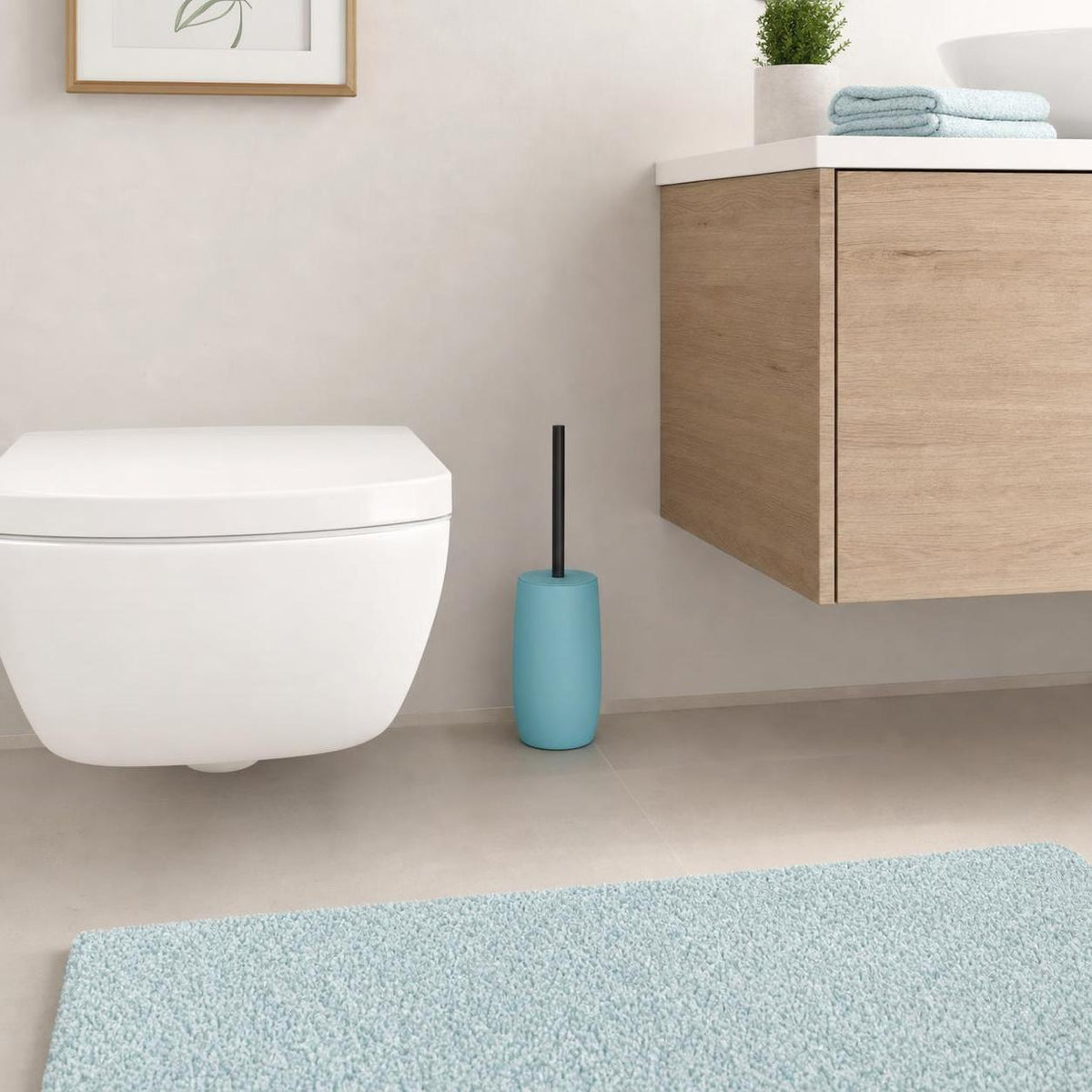 Eine türkisfarbene WC-Bürste steht neben Toilette und Holzwaschtisch.