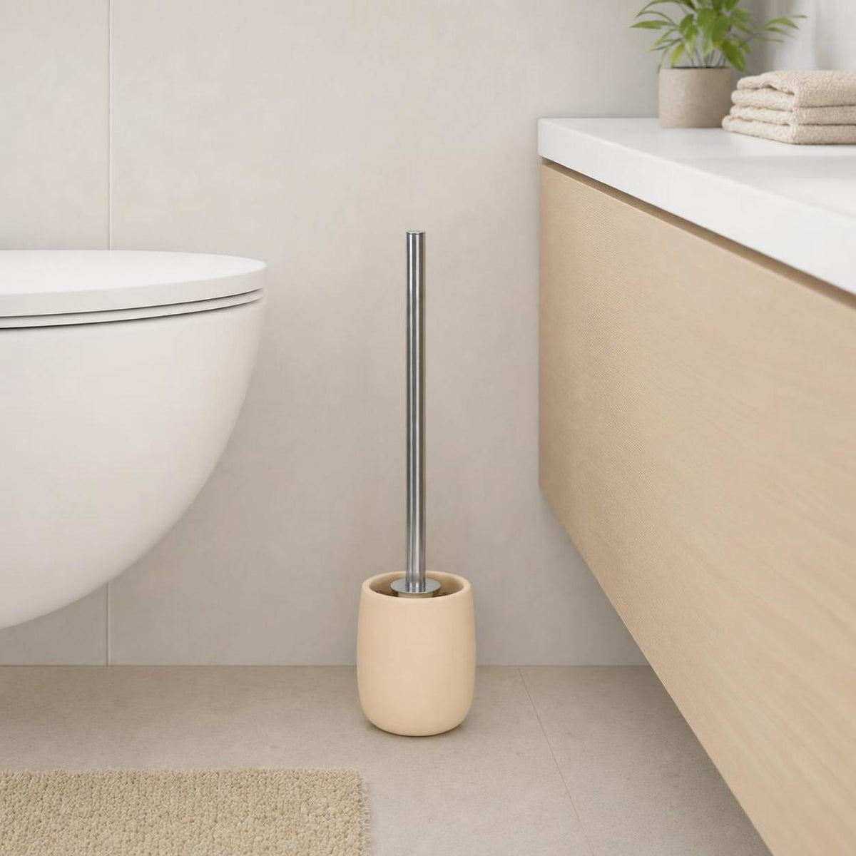 Eine beige WC-Bürste steht neben der Toilette im hellen Bad.