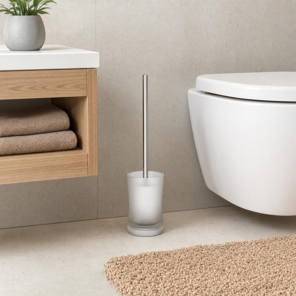 Eine WC-Bürste mit satiniertem Halter steht neben der Toilette.