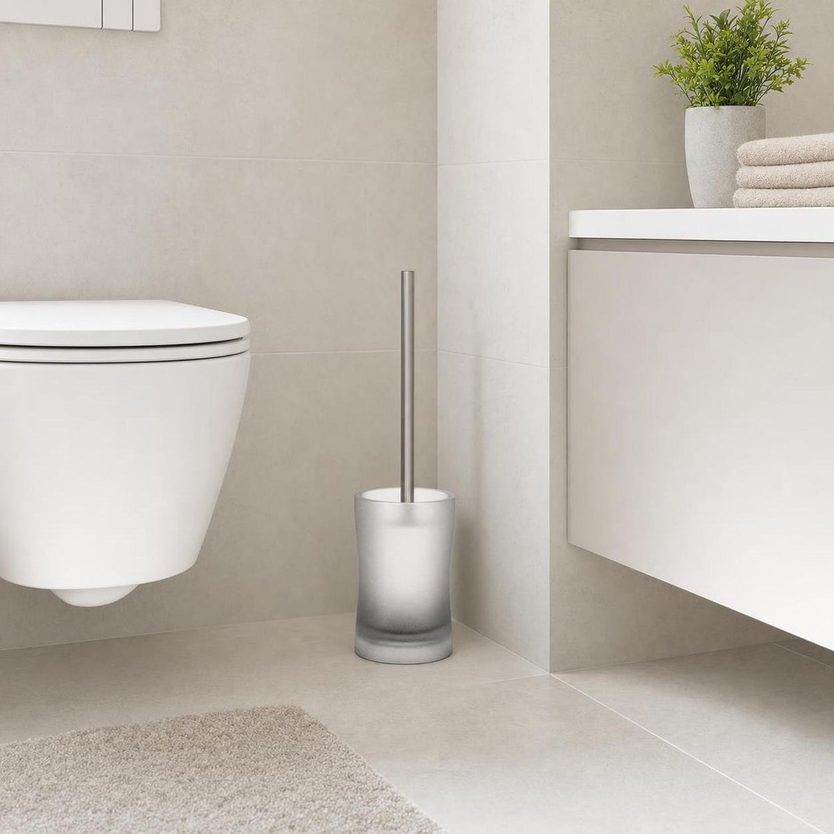 Eine WC-Bürste mit Milchglasbehälter steht neben der Toilette.