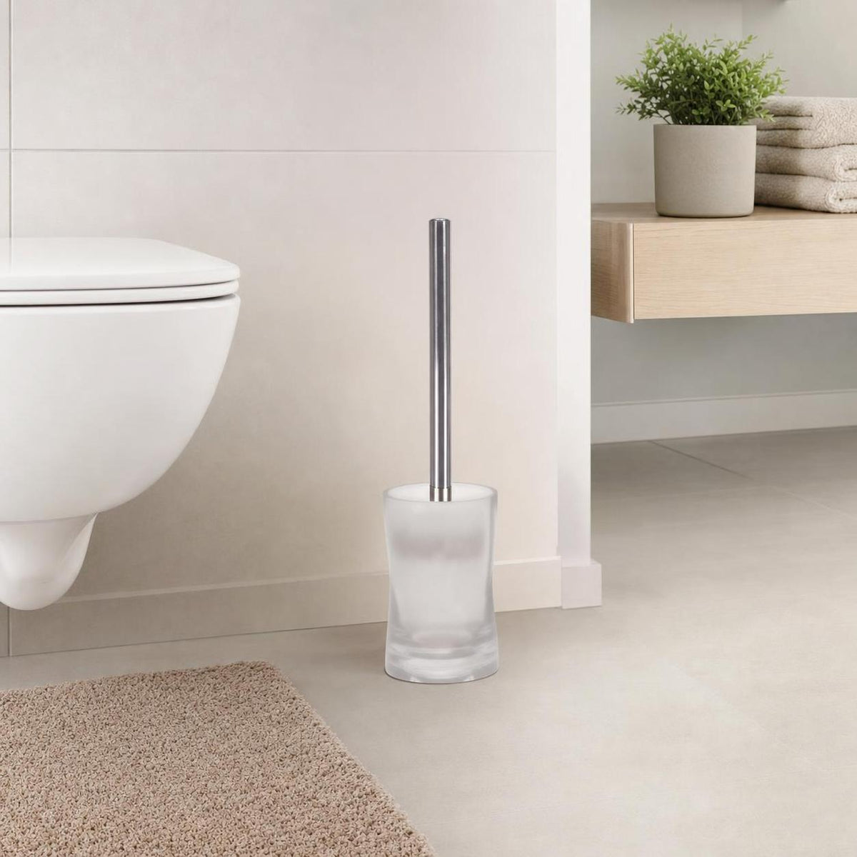 Eine WC-Bürste im satinierten Glasbehälter steht neben der Toilette.