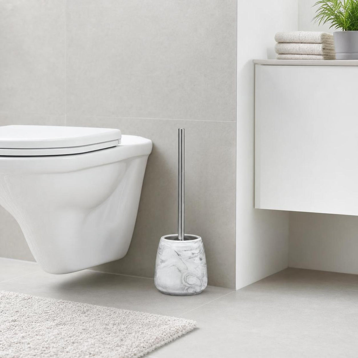 Eine WC-Bürste im Marmorhalter steht neben der Toilette im Bad.