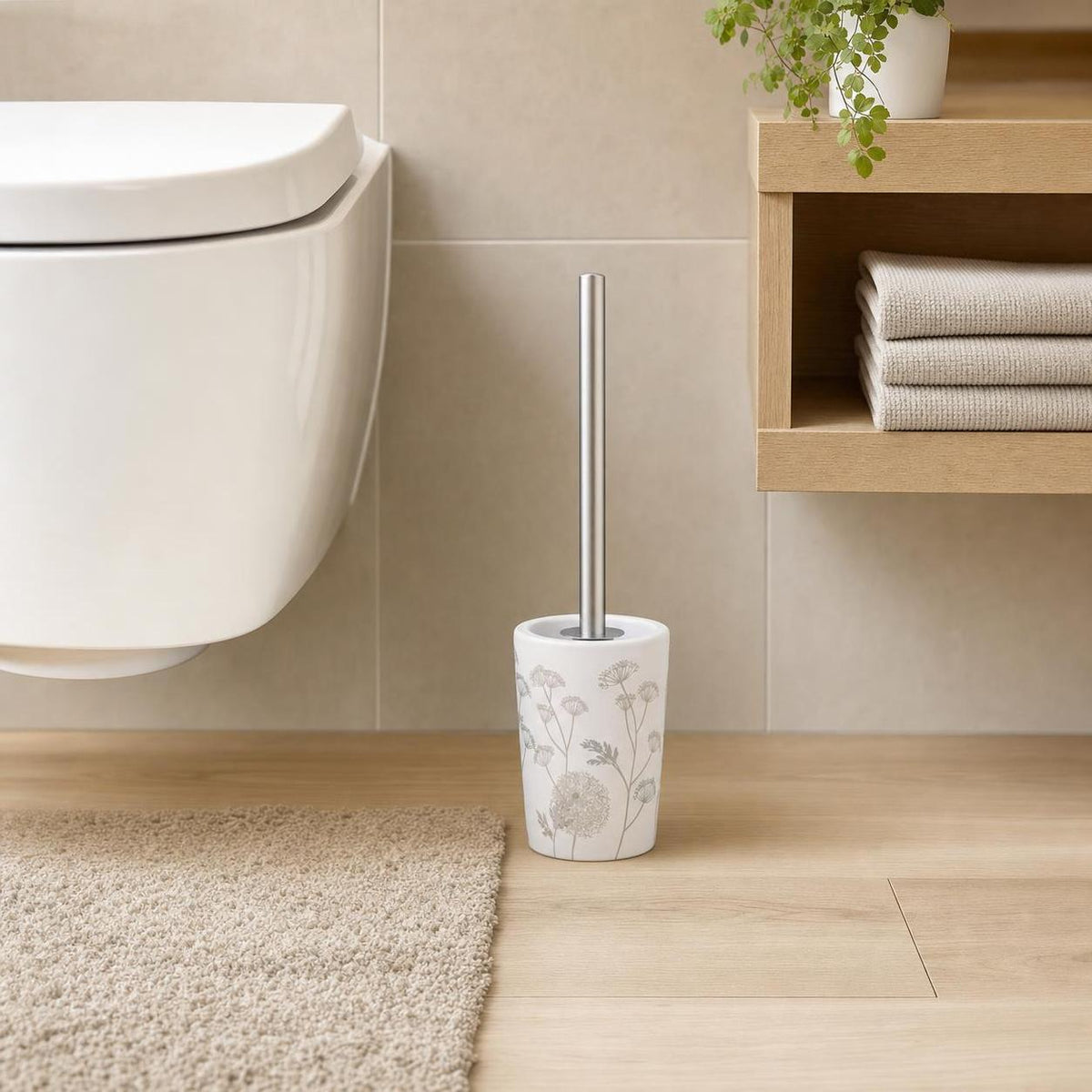 Weiße WC-Bürste mit Blumenmuster steht neben Toilette im Bad.