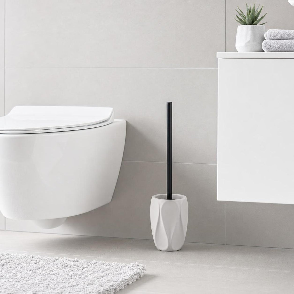 Weiße WC-Bürste mit schwarzem Stiel steht neben der Toilette.