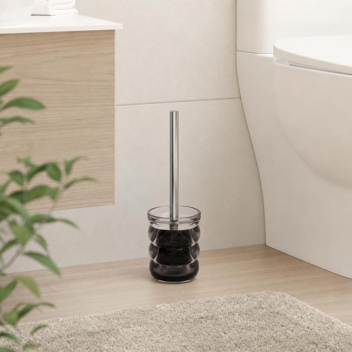 Eine WC-Bürste mit schwarzem Glasbehälter steht neben der Toilette.