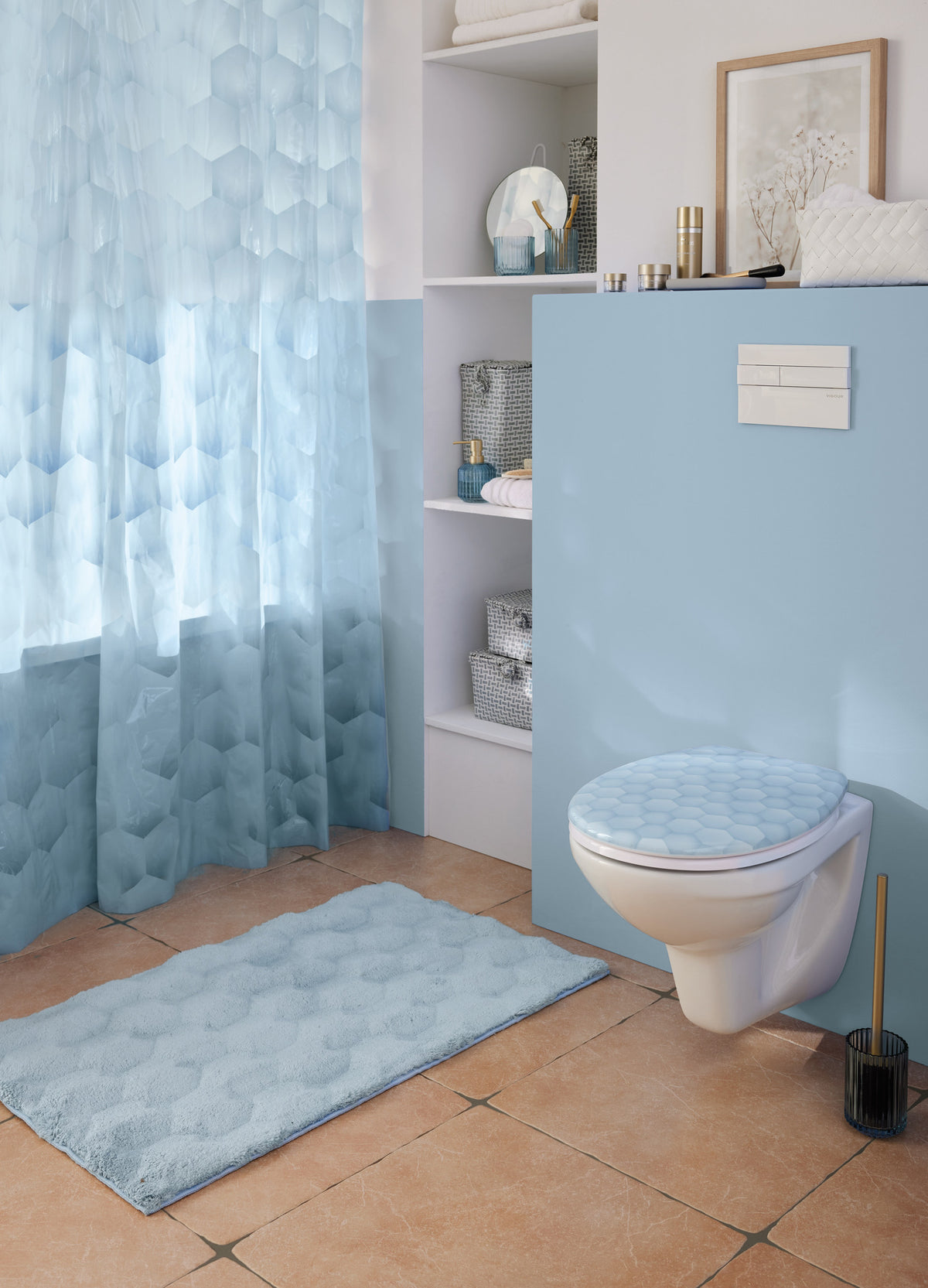 Helles Bad mit blauem Duschvorhang, WC-Sitz und passendem Badteppich.
