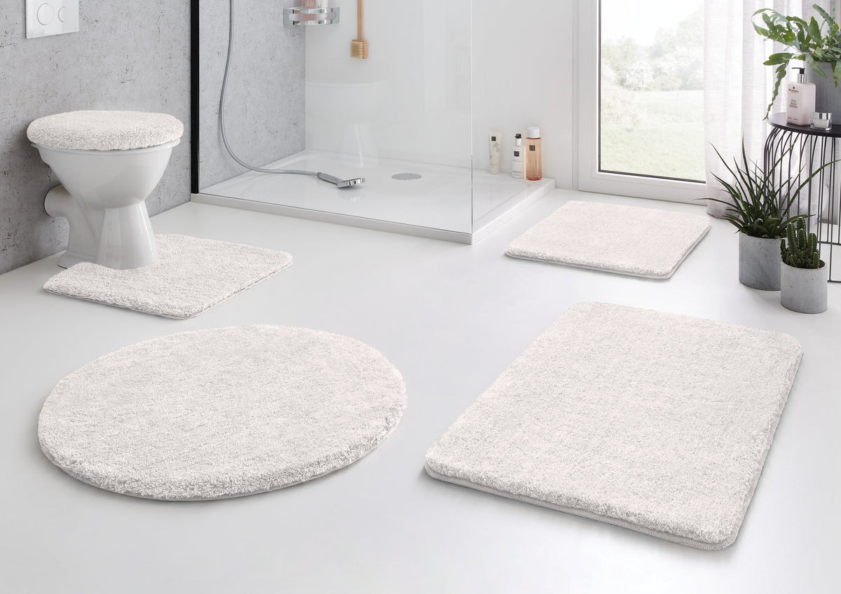 Modernes Bad mit weißem Badematten-Set auf Boden, um Dusche und WC