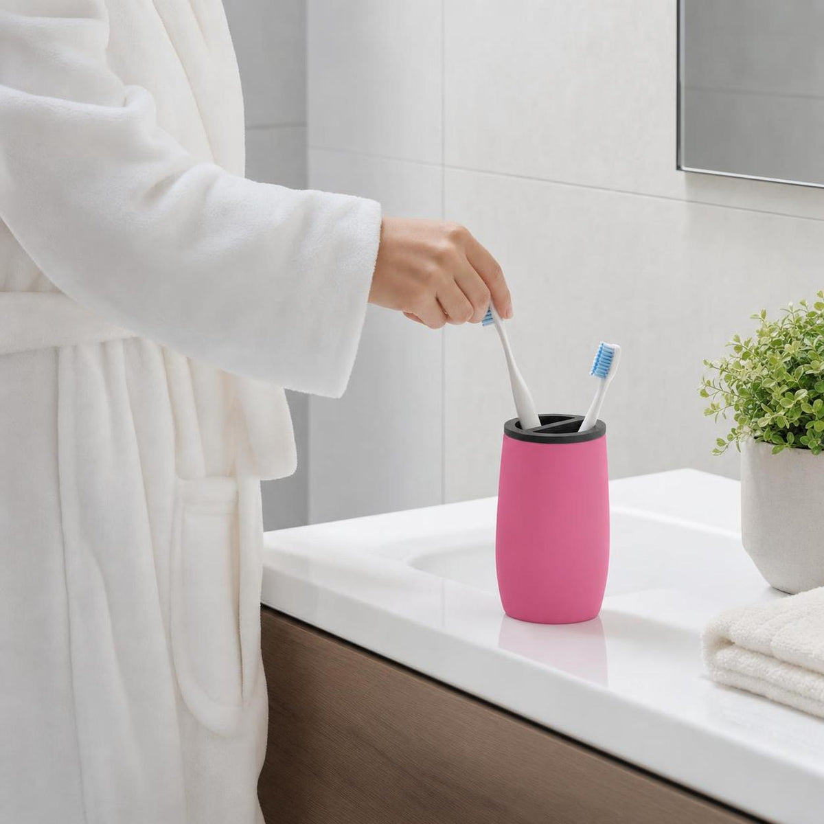 Ein pinker Zahnbürstenhalter steht mit Bürsten auf dem Waschbecken.