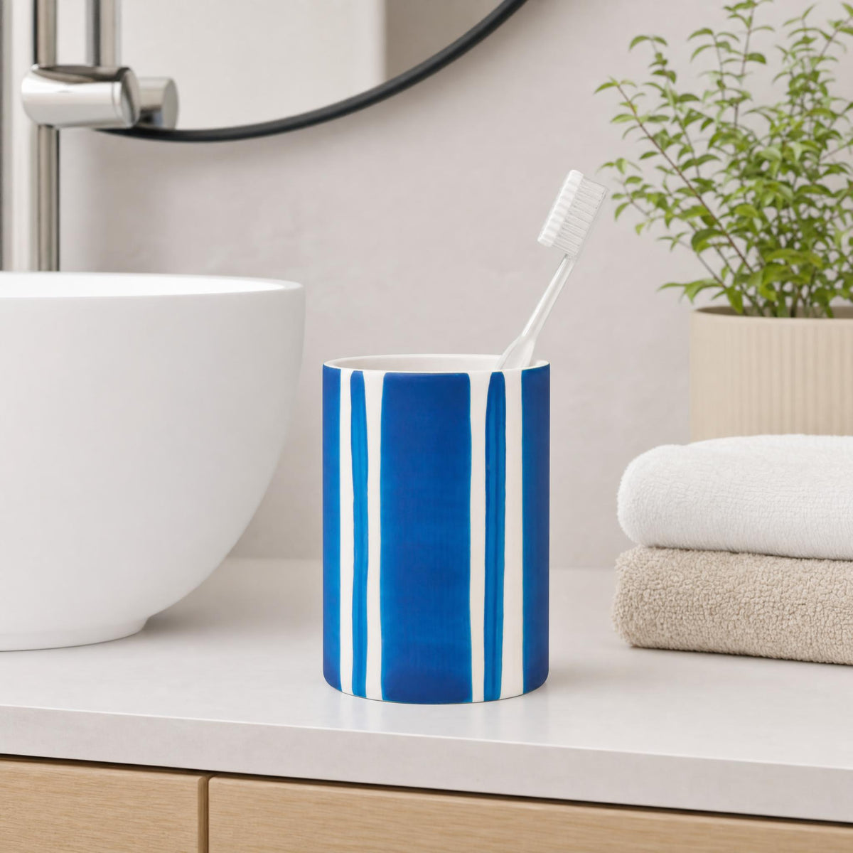 Blau-weißer Zahnputzbecher mit Zahnbürste auf modernem Badezimmerwaschtisch.