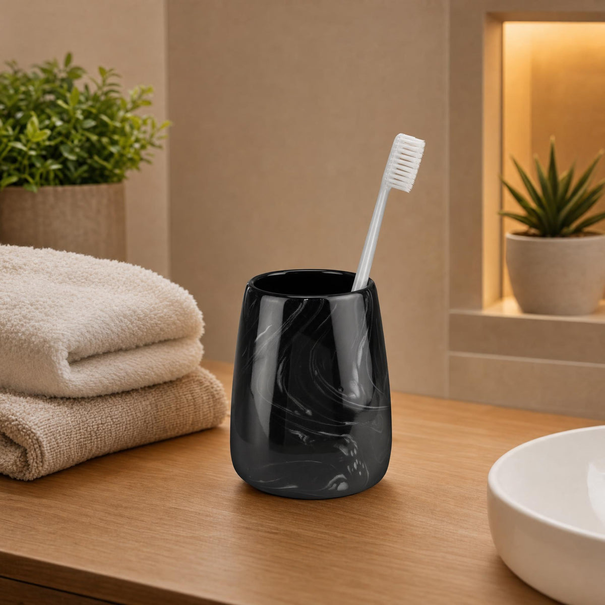 Schwarzer Zahnputzbecher mit Zahnbürste auf Holzablage im Badezimmer.
